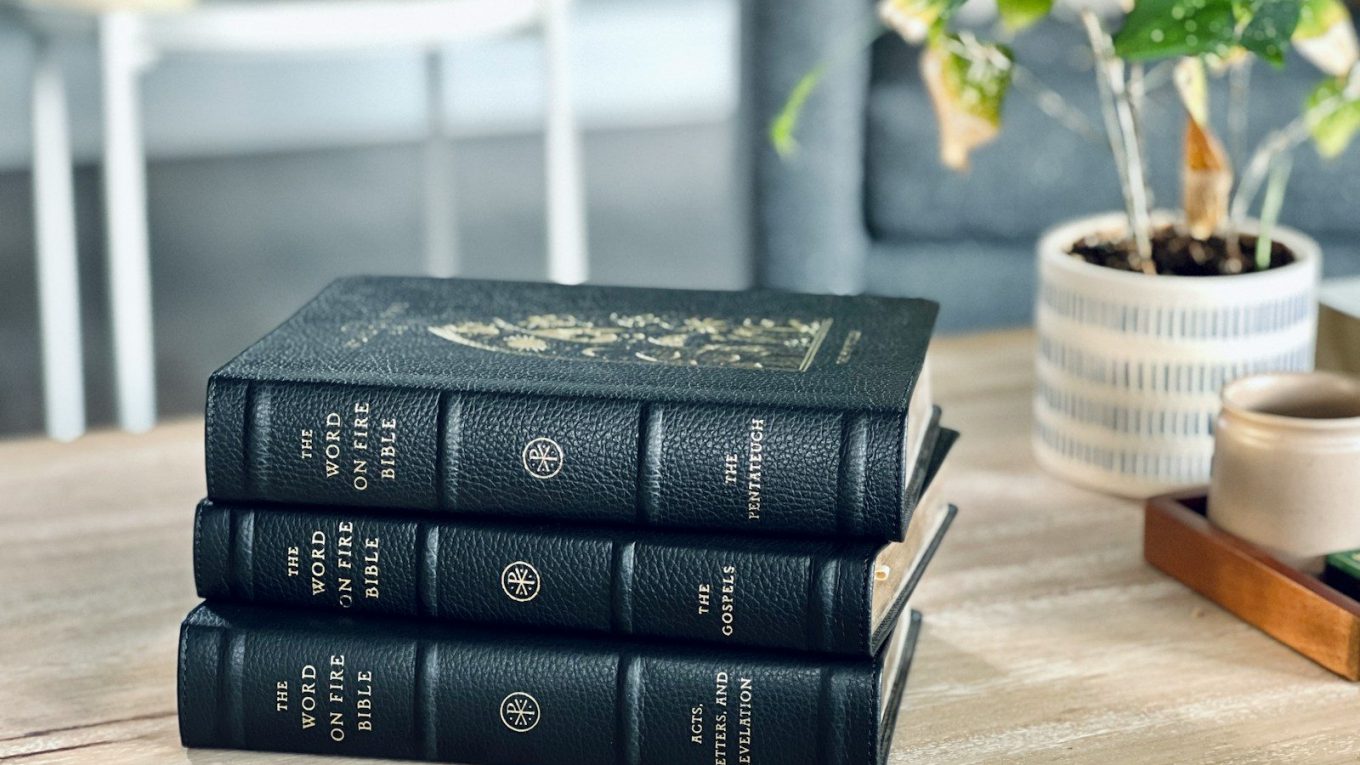 a stack of three books sitting on top of a wooden table