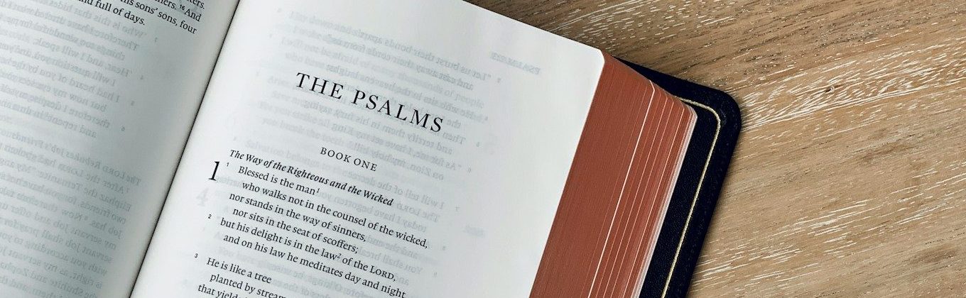 an open book on a wooden table with a ribbon